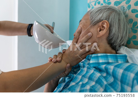Force-feeding,Asian senior woman refuses,does not want to eat food,caregiver scolding,forcing the elderly to eat,old people with no appetite,stop physical abuse,violence,aggression,coercion concept 75193558