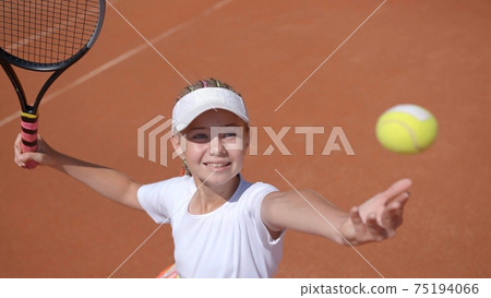A young tennis player serves in the game. A young tennis player serves in the game. 75194066