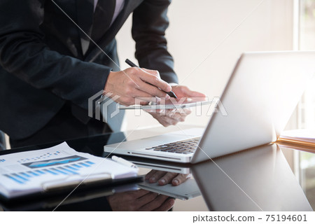 Businessman working at home with tablet and laptop computer and papers on desk. 75194601