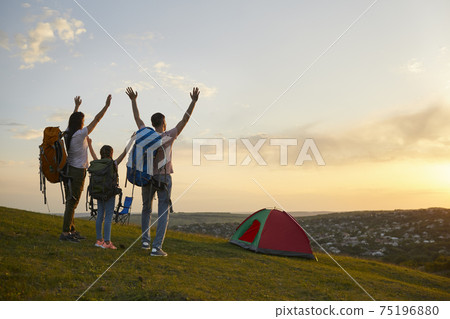Family camping in nature. Parents and child with backpacks enjoying beautiful sunset at campground, copy space Family camping in nature. Parents and child with backpacks enjoying beautiful sunset at campground, copy space 75196880