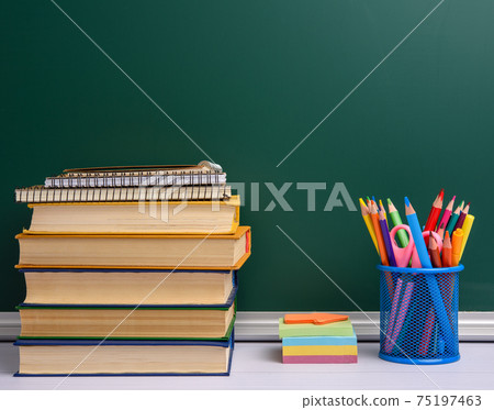 blue stationery glass with multi-colored wooden pencils and pens, green chalkboard background blue stationery glass with multi-colored wooden pencils and pens, green chalkboard background 75197463