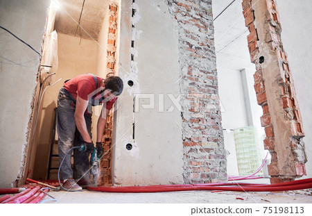 Male worker installing heating system in apartment. Male worker installing heating system in apartment. 75198113