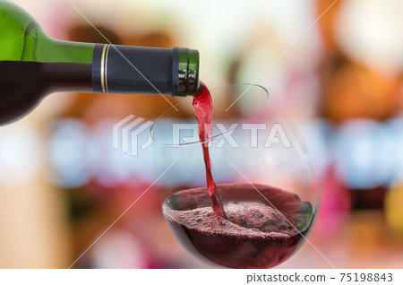 Red wine pouring into a wine glass - celebration concept Red wine pouring into a wine glass - celebration concept 75198843