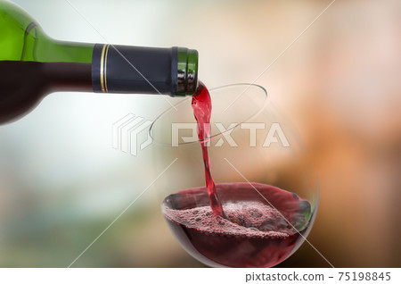 Red wine pouring into a wine glass - celebration concept 75198845