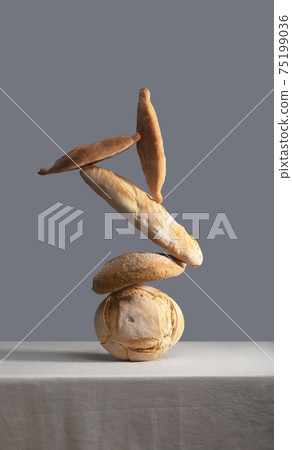 Balancing Bread on a table covered with a tablecloth 75199036