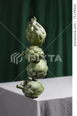 Fresh green artichokes on table. Equilibrium floating food Fresh green artichokes on table. Equilibrium floating food 75199083
