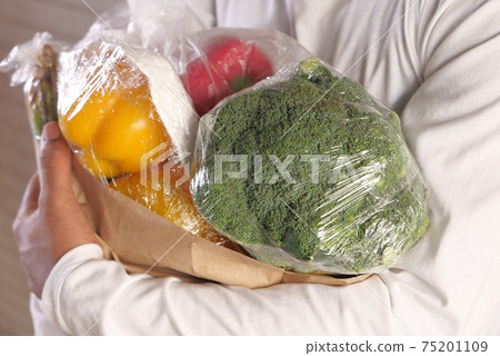 young man carrying vegetables in shopping bag  75201109