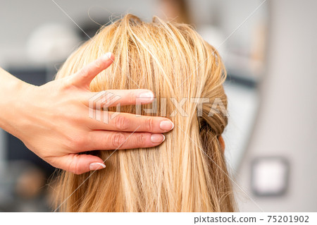Female hairdresser styling blonde hair 75201902