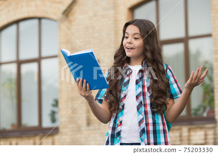Happy kid with long wavy hair in casual style read library Happy kid with long wavy hair in casual style read library 75203330