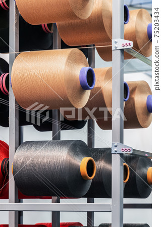 bobbins with threads of different colors on the shelves of a clothing factory bobbins with threads of different colors on the shelves of a clothing factory 75203434