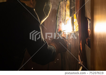 welder welds steel pipe by electric welding welder welds steel pipe by electric welding 75207619