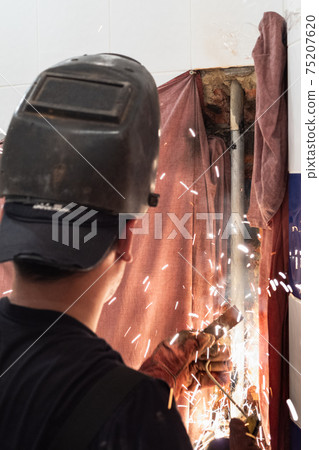 welder welds piece of pipe into plumbing pipe welder welds piece of pipe into plumbing pipe 75207620