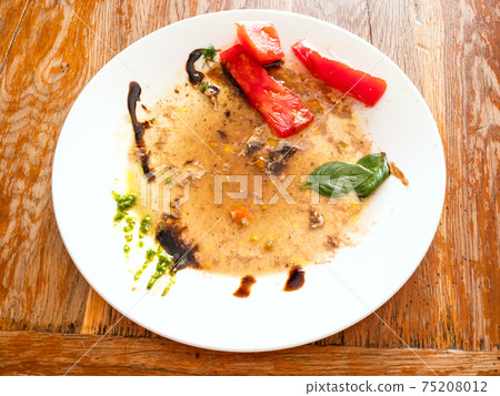 plate with leftover vegetables and sauces on table 75208012