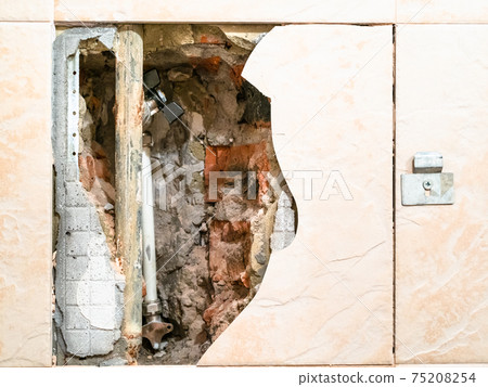 view of old water pipe through broken ceramic tile 75208254