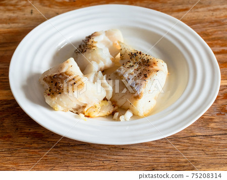 portion of baked cod fish on white plate on table portion of baked cod fish on white plate on table 75208314