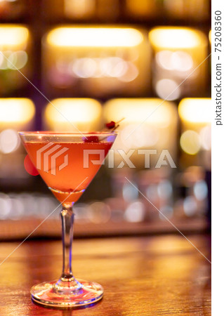 Strawberry juice mixed with alcohol soda in a cocktail glass in front of the vintage bar, Background image light bokeh light orange yellow. Strawberry juice mixed with alcohol soda in a cocktail glass in front of the vintage bar, Background image light bokeh light orange yellow. 75208360