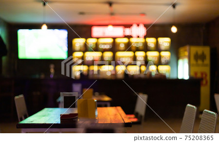 Image is blurred in a bar or tavern. Abstract image of an alcoholic beverage shop or pub. Colorful lighting in a store selling beer, alcohol, cocktails and a wide variety of beverages. Image is blurred in a bar or tavern. Abstract image of an alcoholic beverage shop or pub. Colorful lighting in a store selling beer, alcohol, cocktails and a wide variety of beverages. 75208365