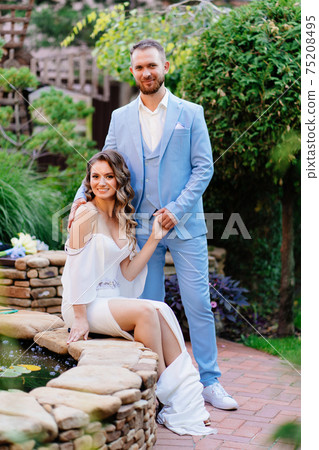 newlyweds near an artificial pond in a summer park. wedding photo shoot. newlyweds near an artificial pond in a summer park. wedding photo shoot. 75208495