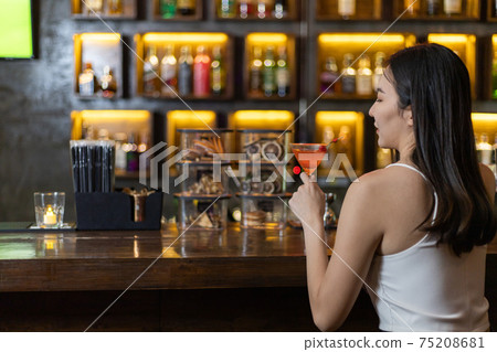 Young Asian woman with a sad face drinking cocktails in front of a vintage bar, Relaxing activities after work or hangouts, Place of entertainment for young adolescents or night club party. Young Asian woman with a sad face drinking cocktails in front of a vintage bar, Relaxing activities after work or hangouts, Place of entertainment for young adolescents or night club party. 75208681