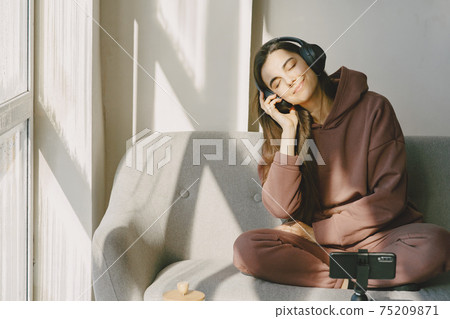 Happy girl in headphones listens to music at home 75209871