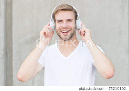 Wireless Earpiece. Handsome guy wear headphones grey Wireless Earpiece. Handsome guy wear headphones grey 75210102