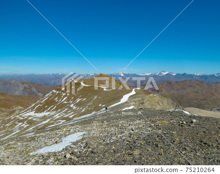 A lonely hiker approaching Piz d'Immez, Switzerland, through a rocky desert A lonely hiker approaching Piz d'Immez, Switzerland, through a rocky desert 75210264