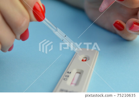 test for coronavirus on a blue background. girl with a bright red manicure makes a blood test. a drop of blood on the sensitive test strip 75210635
