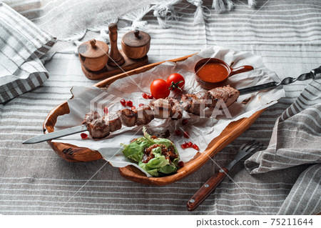 Barbecue with tomatoes and herbs on a wooden plate with paper Barbecue with tomatoes and herbs on a wooden plate with paper 75211644