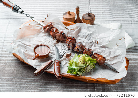 Barbecue with tomatoes and herbs on a wooden plate with paper 75211676