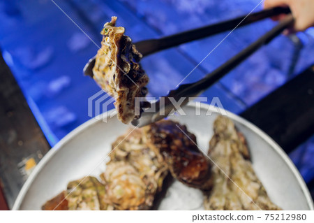 Fresh opened oyster with sliced lemon offered as top view on crushed ice with copy space. 75212980