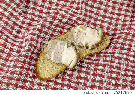 Traditional Ukrainian dish. Baked pork belly with rye bread. Sandwich ready to eat on red checkered cloth. Selective focus. Traditional Ukrainian dish. Baked pork belly with rye bread. Sandwich ready to eat on red checkered cloth. Selective focus. 75217659