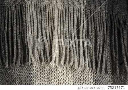 Close-up of fine-checked woolen texture in gray. Winter texture concept, fringe scarf, knitted clothing. Machine knitted woolen goods. Selective focus, noisy texture. Close-up of fine-checked woolen texture in gray. Winter texture concept, fringe scarf, knitted clothing. Machine knitted woolen goods. Selective focus, noisy texture. 75217671