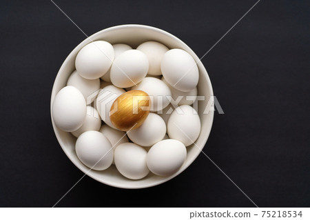 Golden egg is on top of white ones on black background 75218534