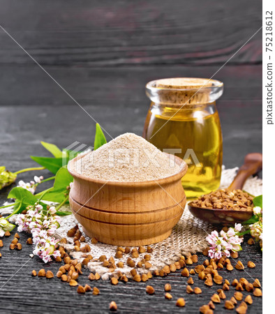 Flour buckwheat brown in bowl with oil on black board 75218612