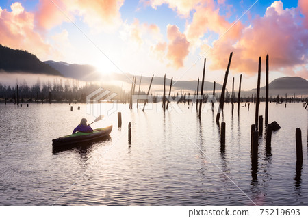 Adventurous Girl kayaking on an infatable kayak in a beautiful lake Adventurous Girl kayaking on an infatable kayak in a beautiful lake 75219693