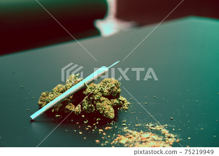 Cannabis buds and other smoking utensils on a table 75219949