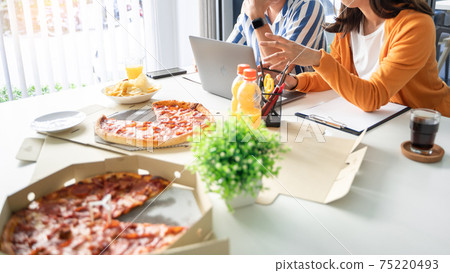 Business team workers discussing work and prepare pizza and potato chips to sharing meal at lunch break for good relations in office. Business team workers discussing work and prepare pizza and potato chips to sharing meal at lunch break for good relations in office. 75220493