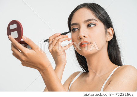 mixed race asian woman putting eye liner on eyelid 75221662
