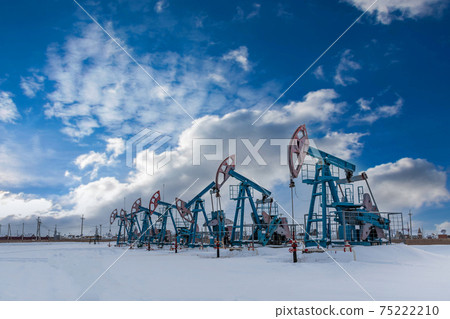 Several Oil pumpjack under the blue sky with clouds winter working. 75222210