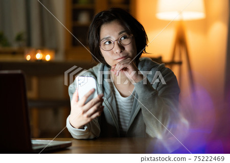 A young woman having a zoom conversation on her smartphone in the living room at night A young woman having a zoom conversation on her smartphone in the living room at night 75222469