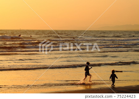 Children playing on the beach at dusk (silhouette) 75224423
