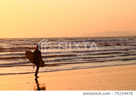 衝浪者(女性)黃昏時沿著海岸線走 衝浪者(女性)黃昏時沿著海岸線走 75224478