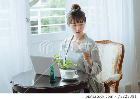 一個使用計算機進行無現金付款的年輕女子 一個使用計算機進行無現金付款的年輕女子 75225381