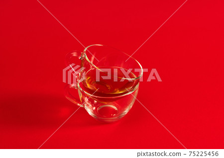 Two transparent glass cups on a red surface. Shot with soft shadow on red background with copy space 75225456