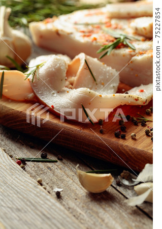 Lard with spices and herbs on a old wooden table. 75227854