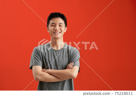 Portrait of Asian handsome man with arms crossed isolate on red background with copy space for text 75228011