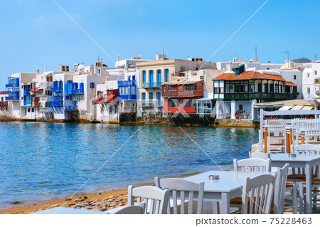 Beautiful Little Venice, Mykonos, Greece. Romantic neighborhood with whitewashed bars, cafes, restaurants. Colorful tables and chairs by shoreline 75228463