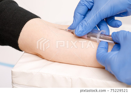 Nurse takes a blood sample from arm vein performing a venipuncture Nurse takes a blood sample from arm vein performing a venipuncture 75229521