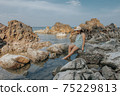 Beautiful woman walking on rock over sea 75229813