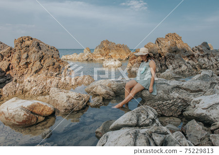 Beautiful woman walking on rock over sea 75229813
